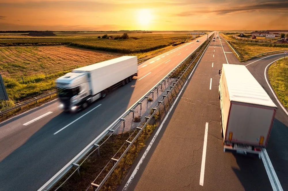 Two trucks driving on open road