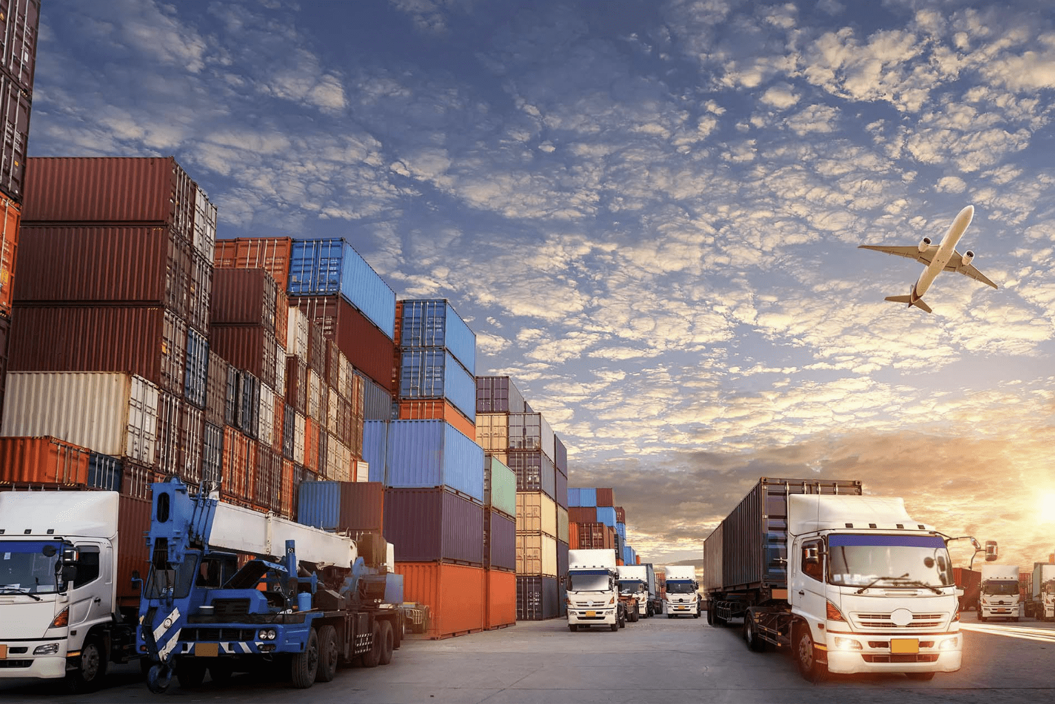 Shipping containers and trucks at sunset