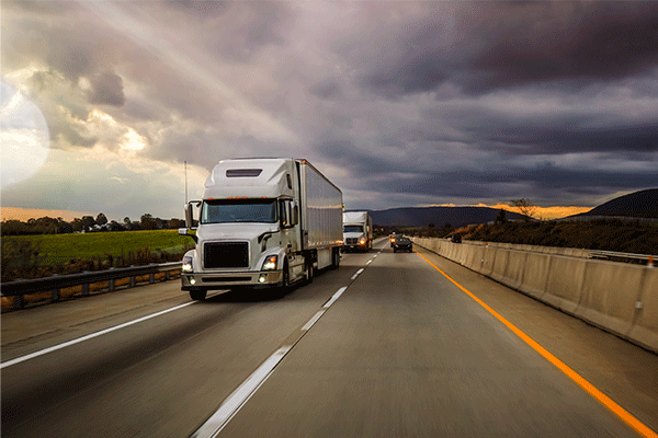 White semis heading down stormy highway