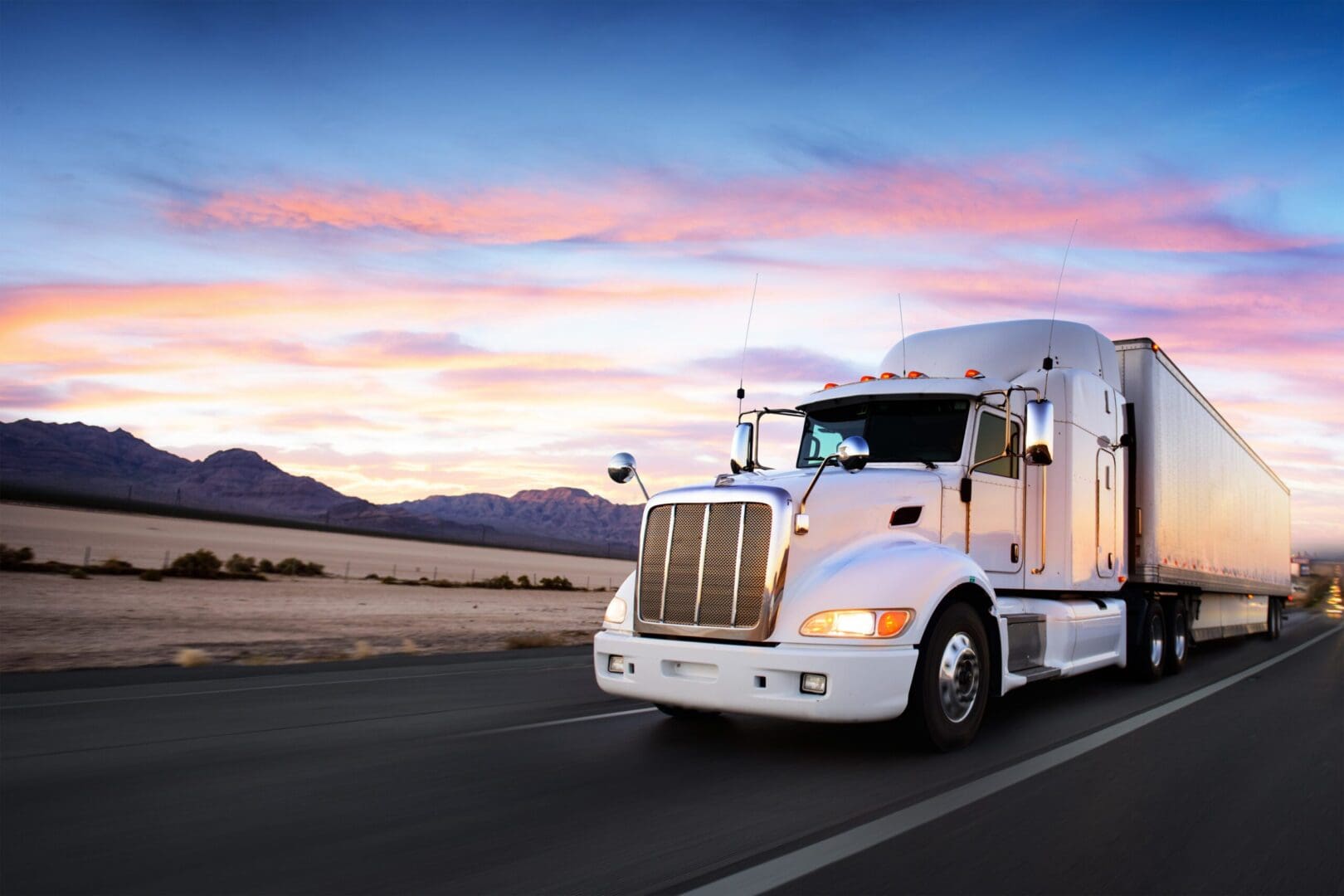 Semi-truck on open road during sunset