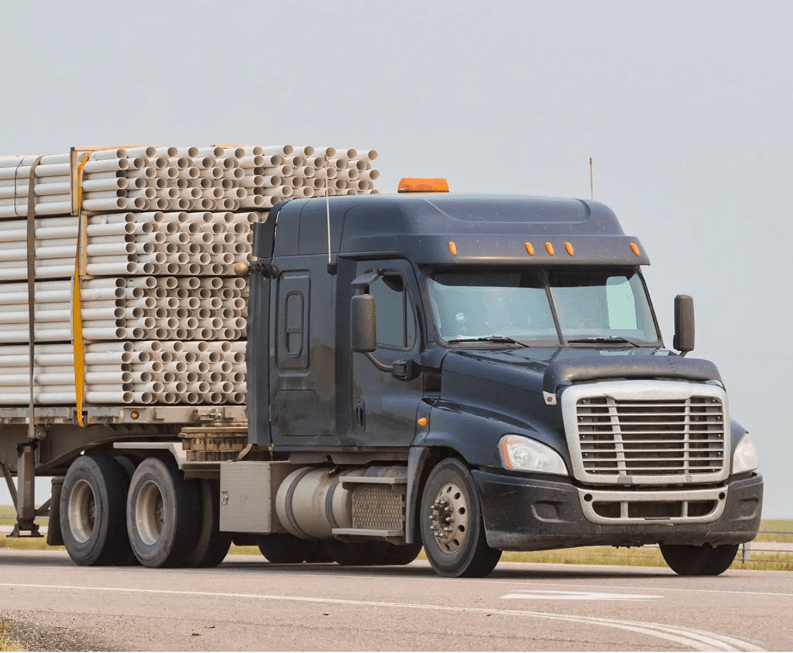 Freight truck on highway carrying pipes