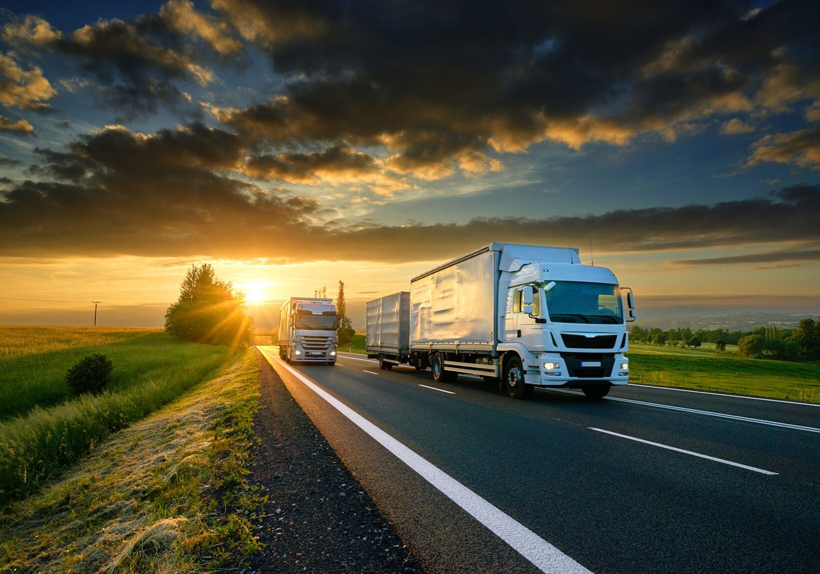 Sunset behind trucks on countryside road