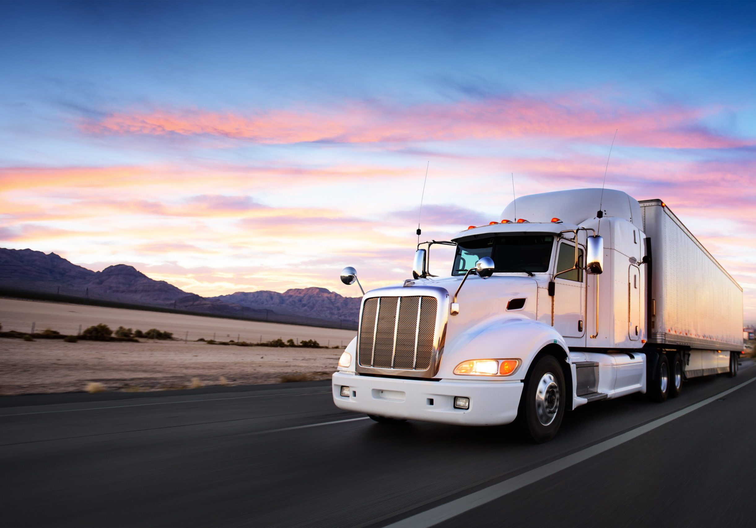 Semi-truck on open road during sunset